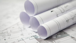Blue prints on a table with rolled blueprints