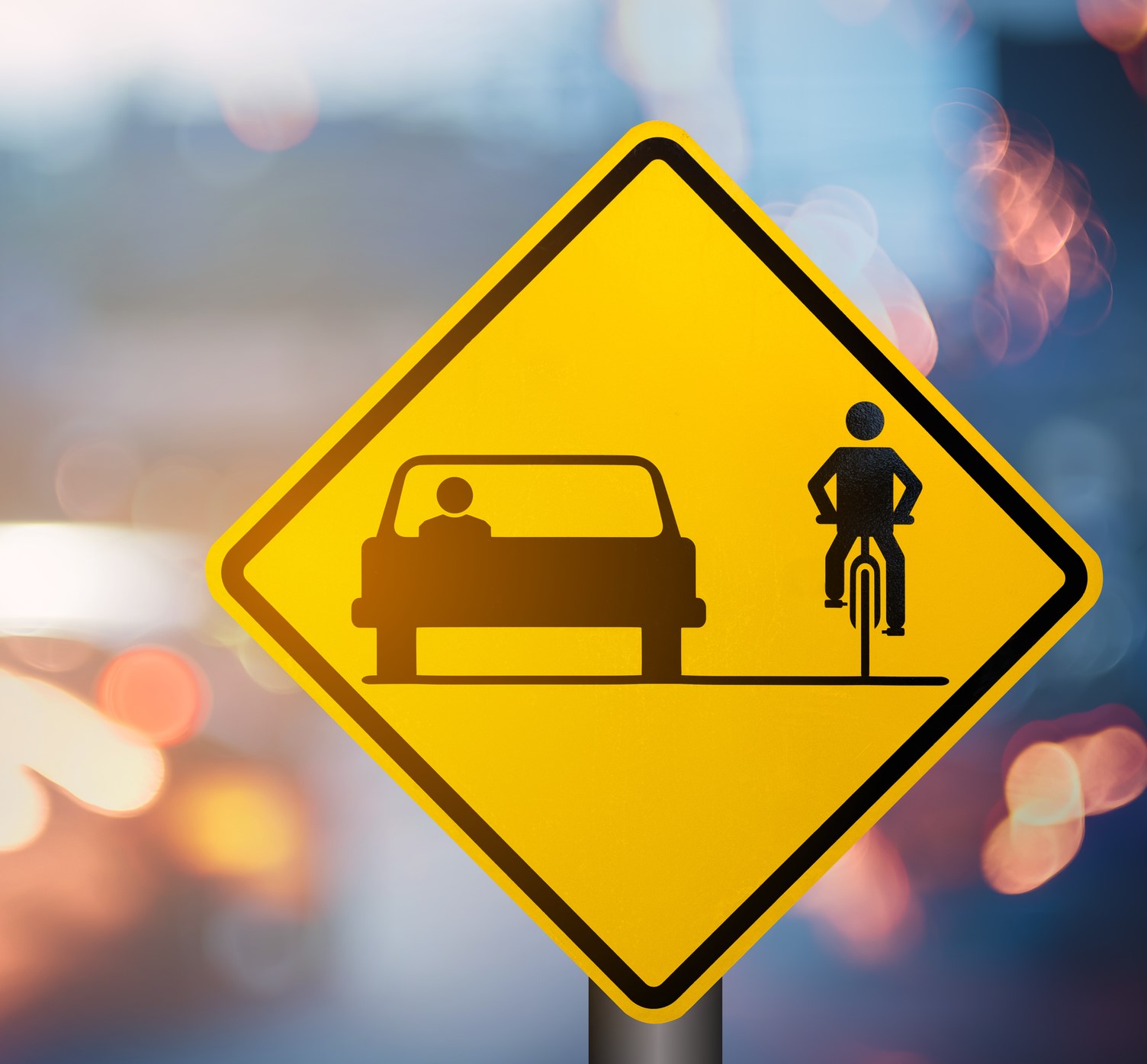 Bicycle and car share warning sign on blur traffic road with colorful bokeh light abstract background. Copy space of transportation and travel concept. Vintage tone filter color style. Bicycle and car share warning sign on blur traffic road with colorful bokeh light abstract background. Copy space of transportation and travel concept. Vintage tone filter color style.