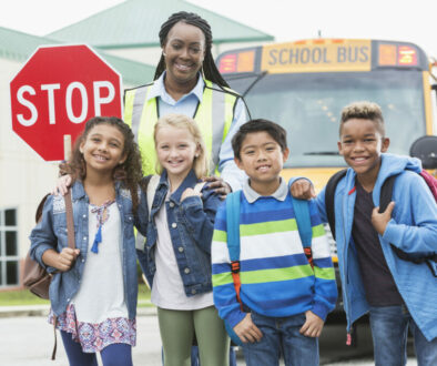 Children, crossing guard standing in front of school bus