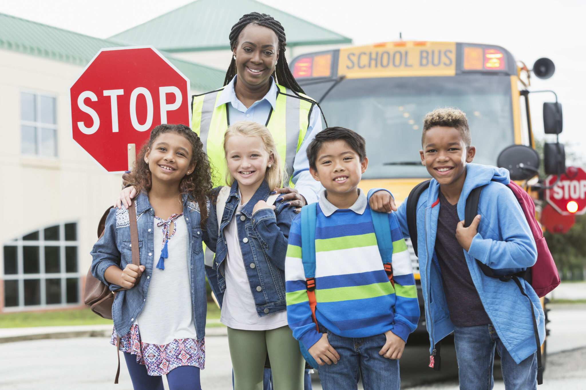 Children, crossing guard standing in front of school bus